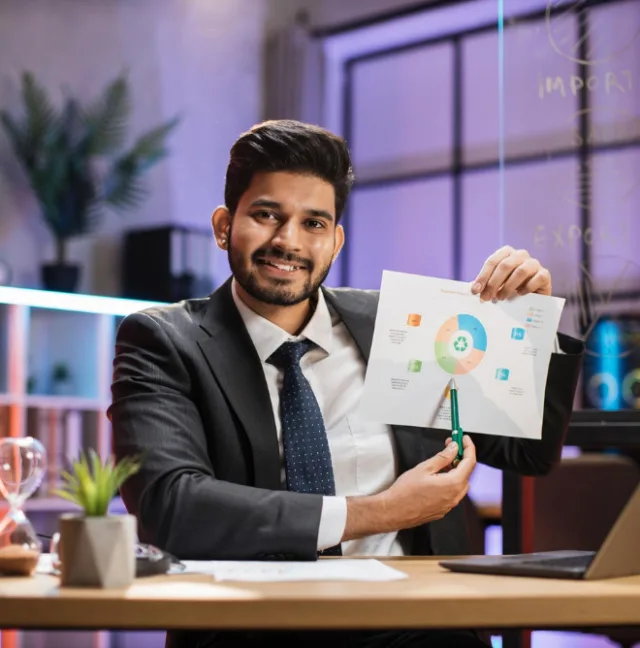 A business owner at his desk holding up a chart while planning funds for growth